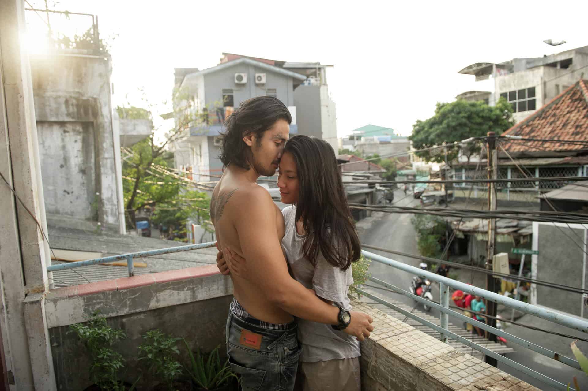 A couple hugging on a balcony in a still from A Copy of My Mind