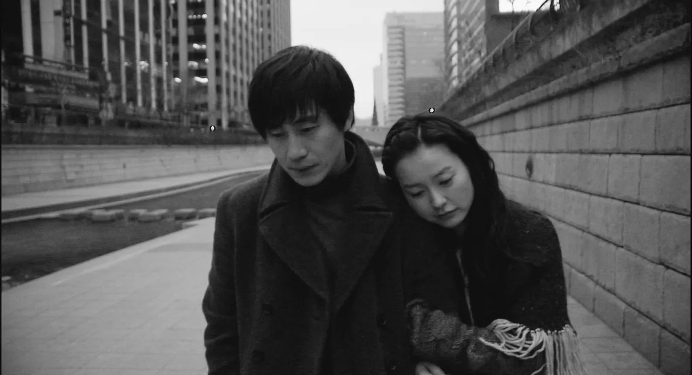 Black and white movie still of a couple strolling from Cafe Noir
