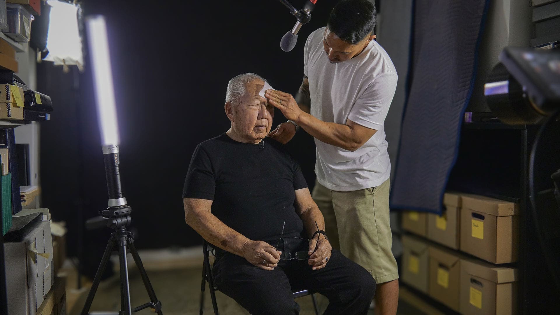 Tadashi Nakamura wipes the sweat off the brow of his aging father, Robert Nakamura, in a studio.